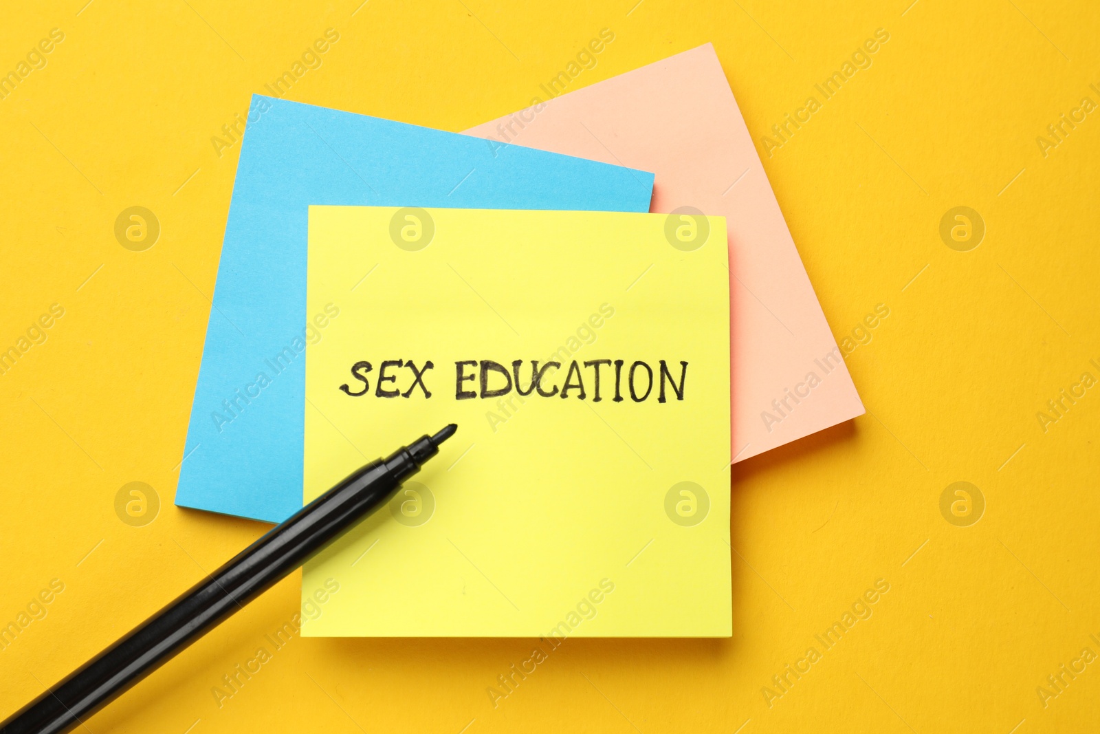 Photo of Sticky notes with words Sex Education and felt pen on yellow background, flat lay