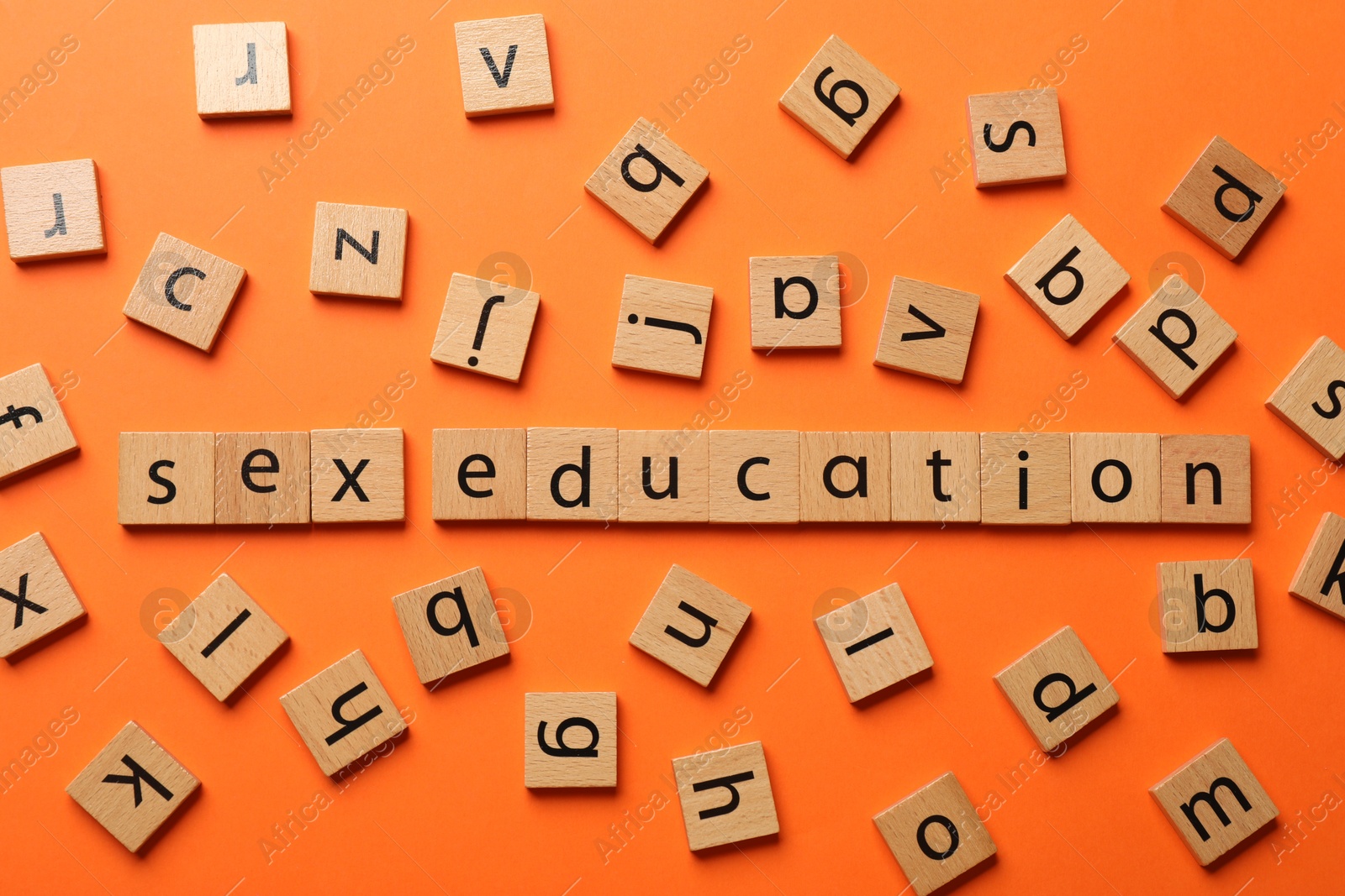 Photo of Words Sex Education made of wooden squares with letters on orange background, flat lay