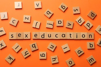 Photo of Words Sex Education made of wooden squares with letters on orange background, flat lay