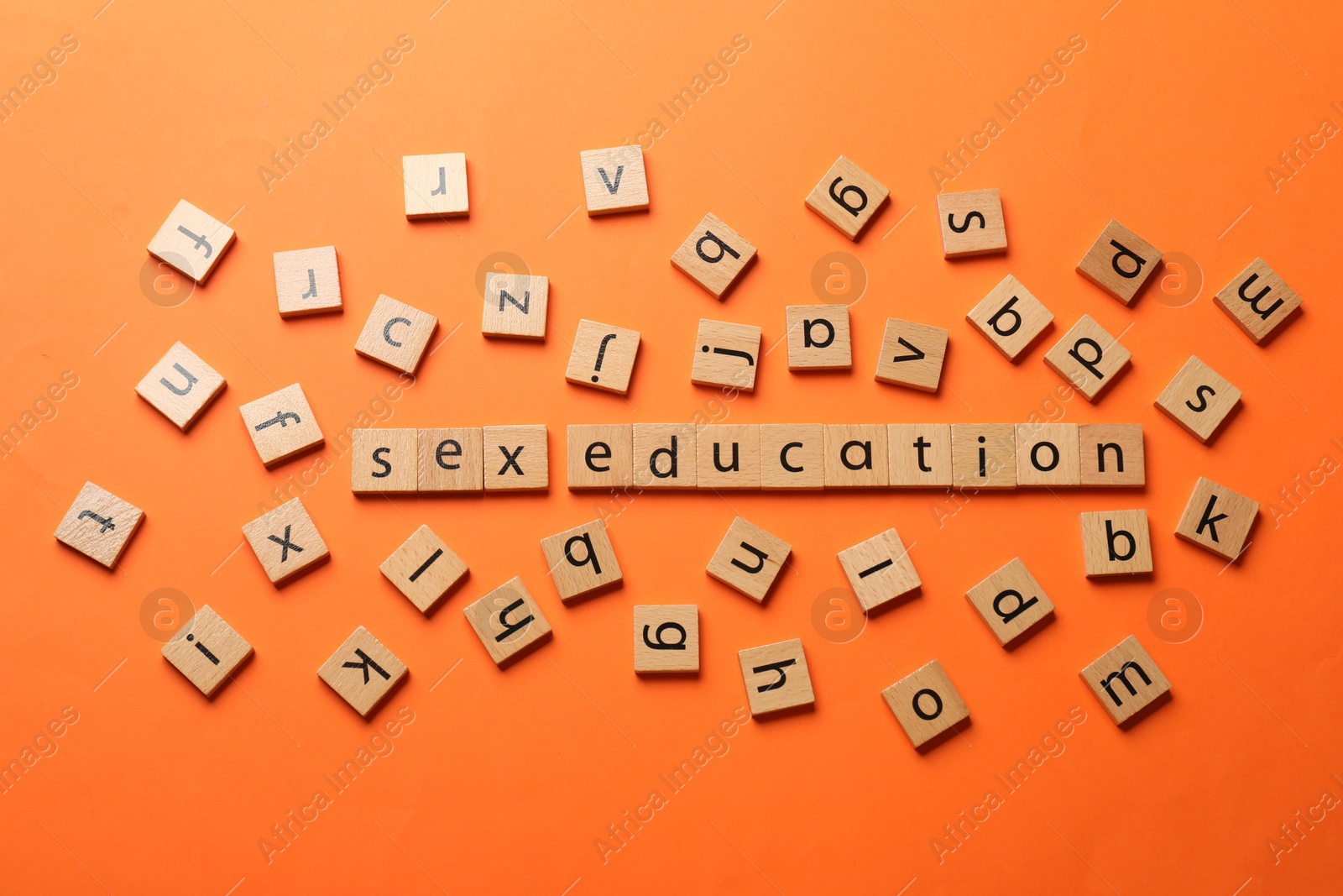 Photo of Words Sex Education made of wooden squares with letters on orange background, flat lay