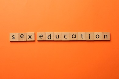 Photo of Words Sex Education made of wooden squares on orange background, flat lay