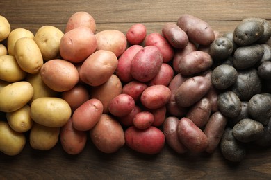 Photo of Different types of potatoes on wooden table, flat lay