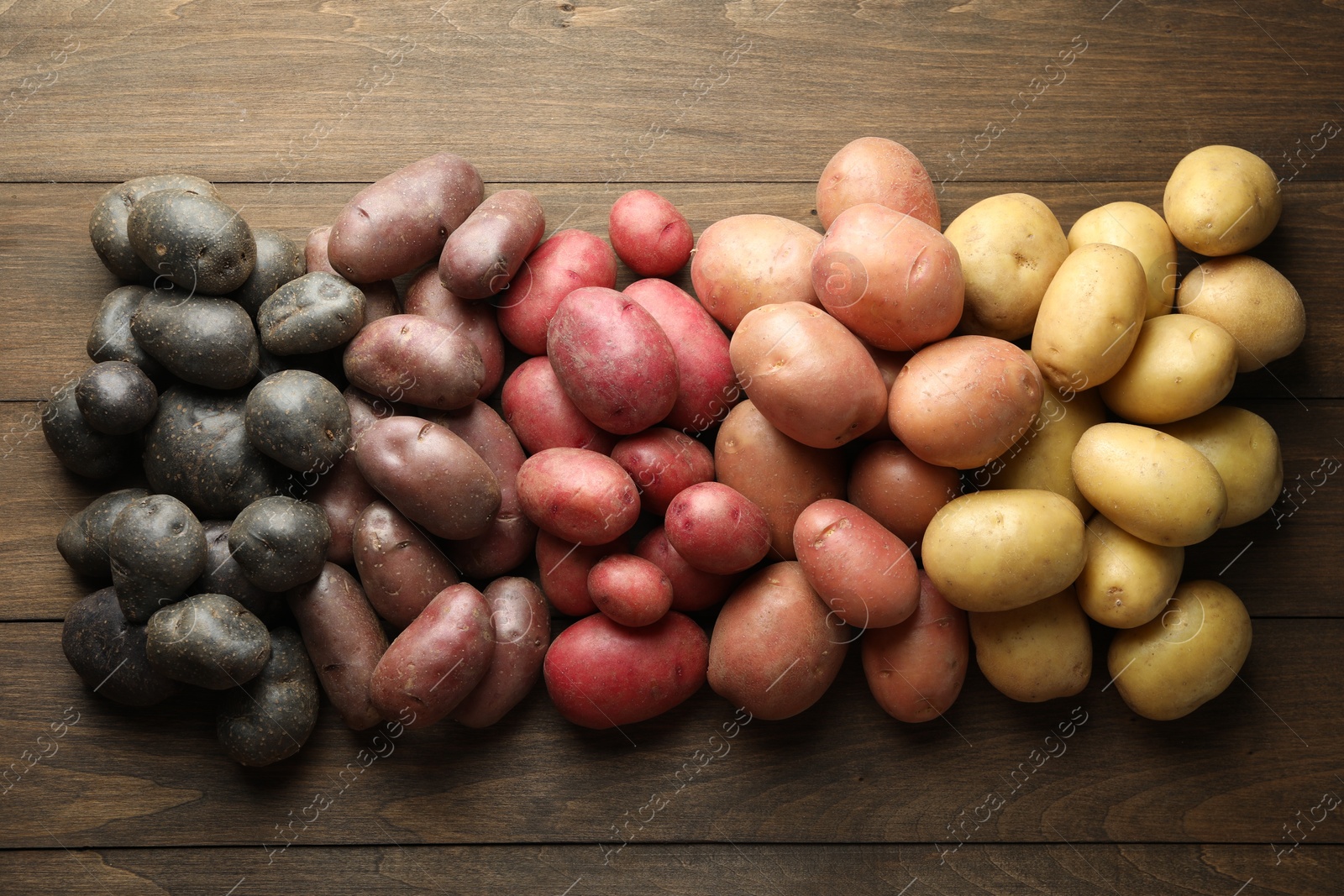 Photo of Different types of potatoes on wooden table, flat lay