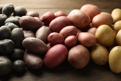 Photo of Different types of potatoes on wooden table, closeup