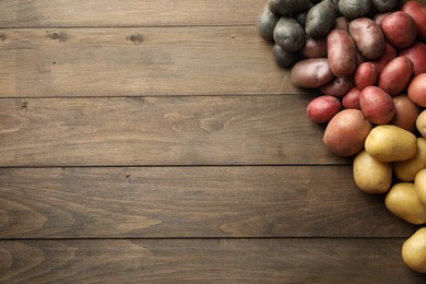Photo of Different types of potatoes on wooden table, flat lay. Space for text