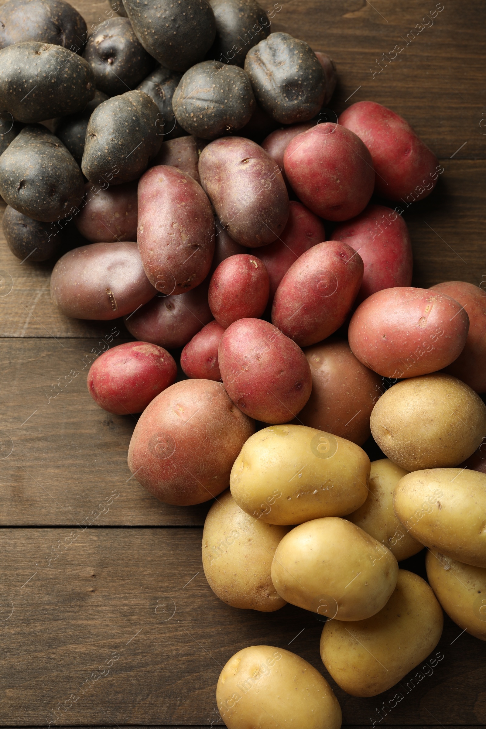 Photo of Different types of potatoes on wooden table, above view
