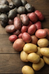 Photo of Different types of potatoes on wooden table, above view