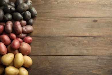 Photo of Different types of potatoes on wooden table, flat lay. Space for text