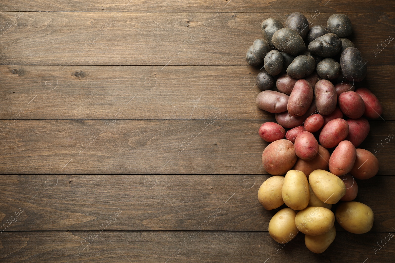 Photo of Different types of potatoes on wooden table, flat lay. Space for text