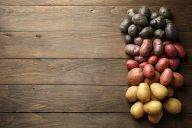 Photo of Different types of potatoes on wooden table, flat lay. Space for text