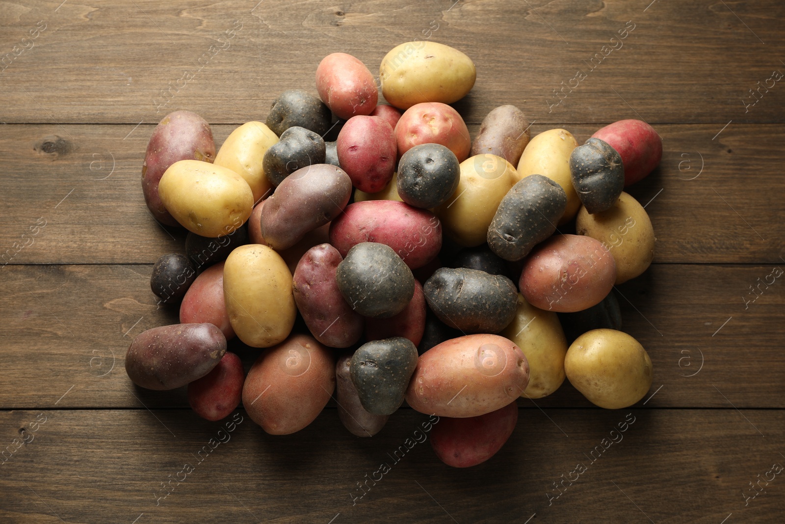 Photo of Different types of potatoes on wooden table, flat lay