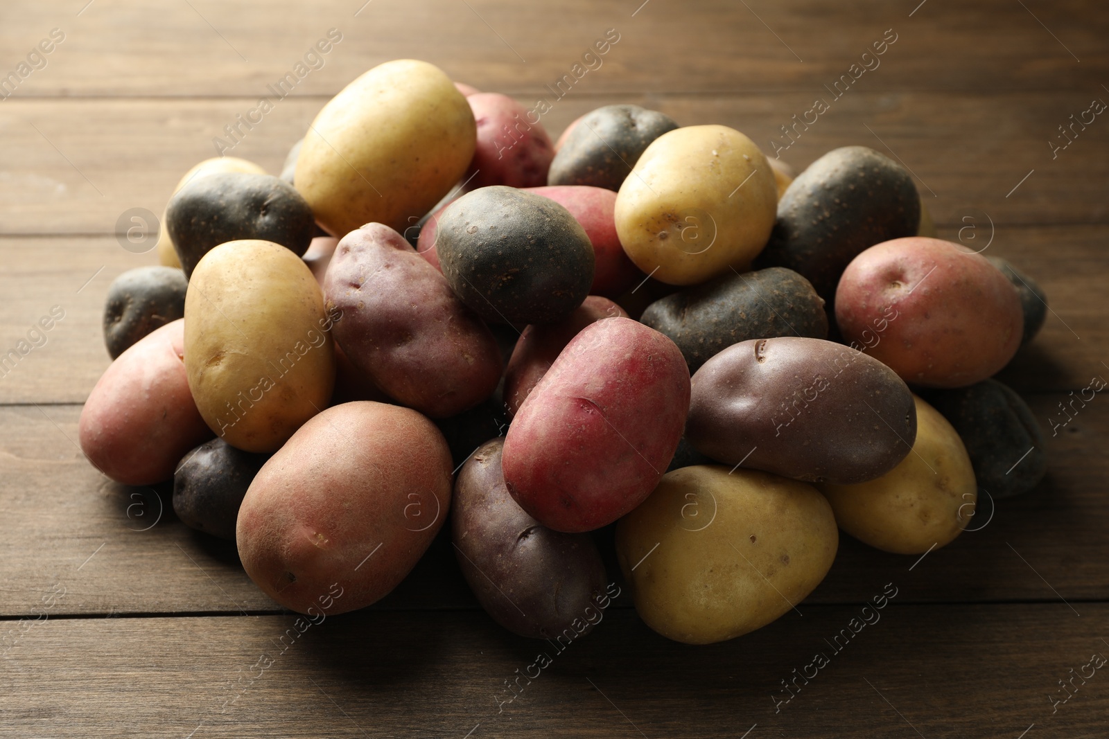 Photo of Different types of potatoes on wooden table, closeup