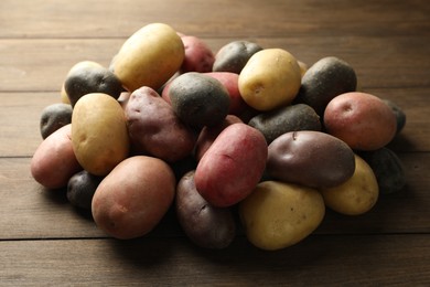 Photo of Different types of potatoes on wooden table, closeup