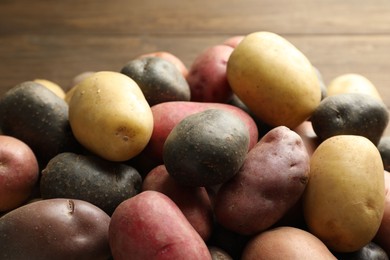 Photo of Different types of potatoes on wooden table, closeup