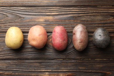 Photo of Different types of potatoes on wooden table, flat lay