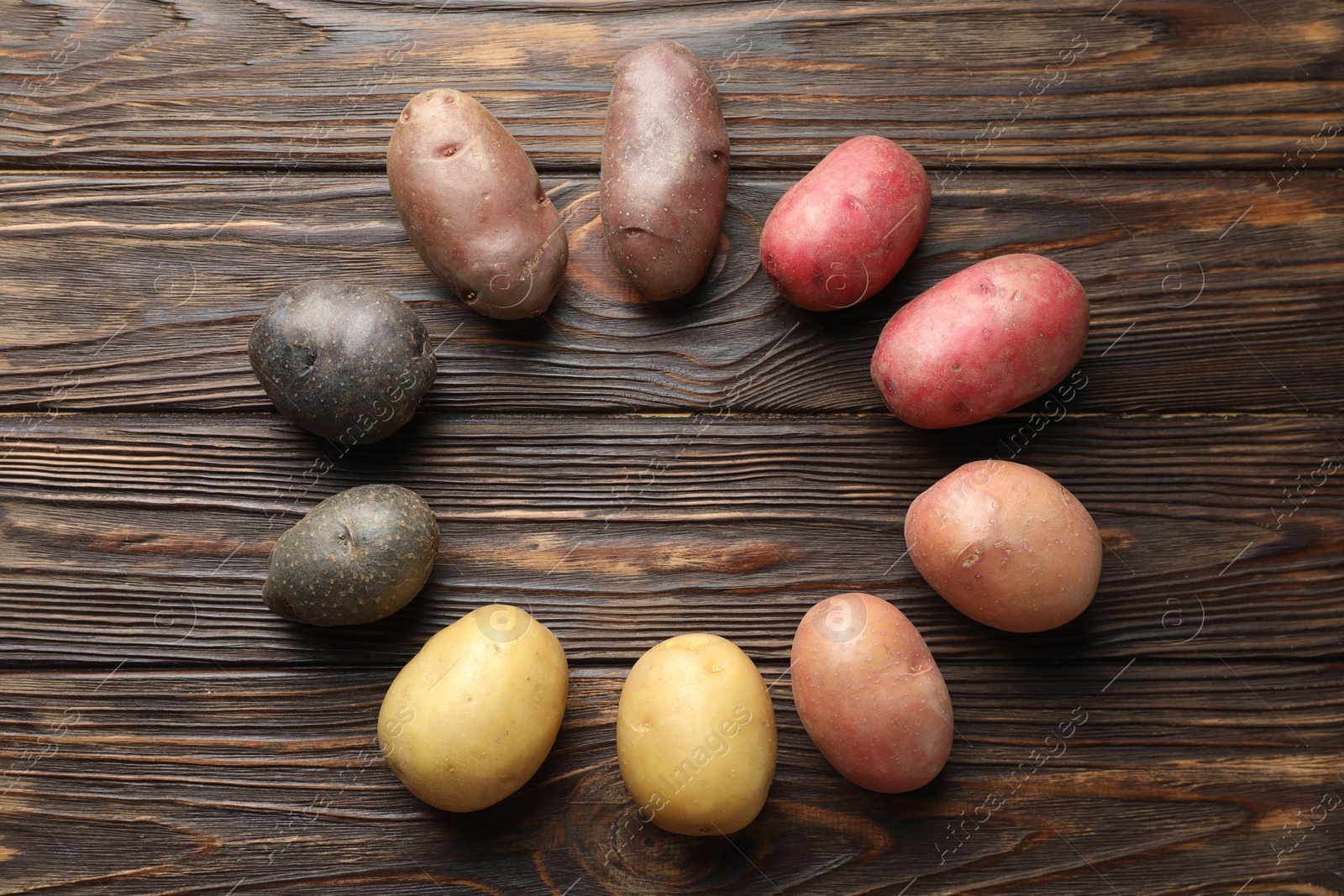 Photo of Different types of potatoes on wooden table, flat lay. Space for text