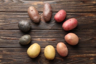 Photo of Different types of potatoes on wooden table, flat lay. Space for text