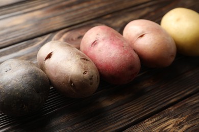 Photo of Different types of potatoes on wooden table, closeup