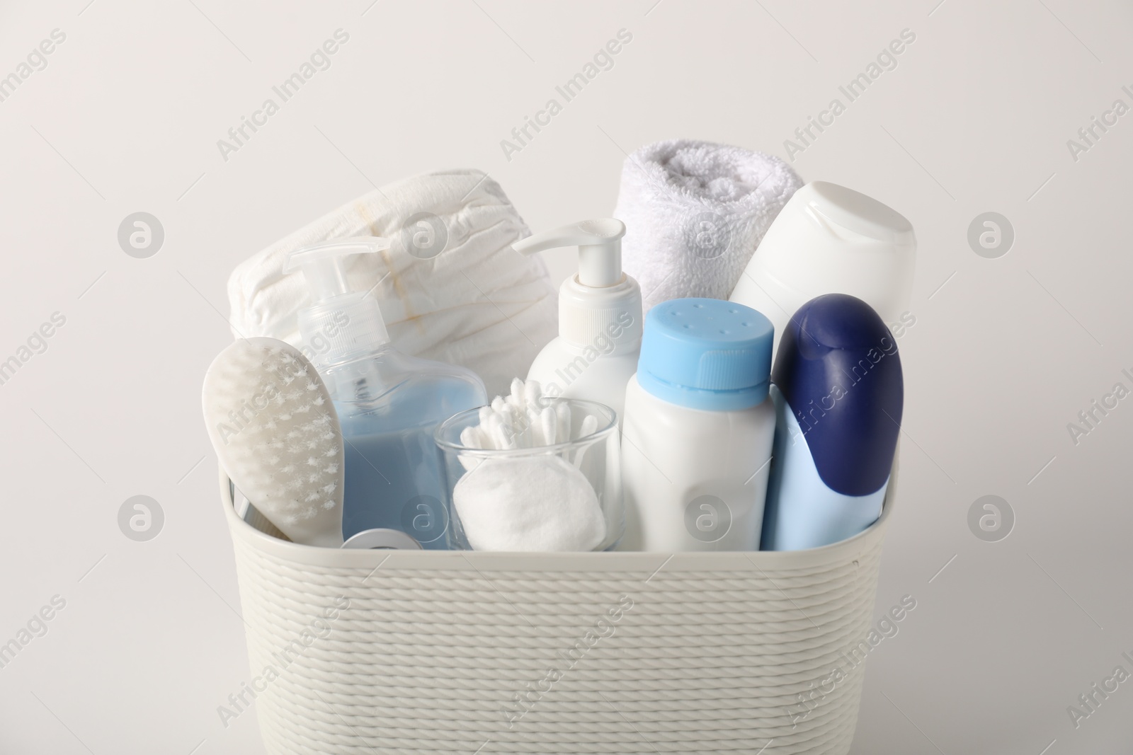 Baby accessories and body care products in basket on light grey background, closeup Photo of Baby accessories and body care products in basket on light grey background, closeup