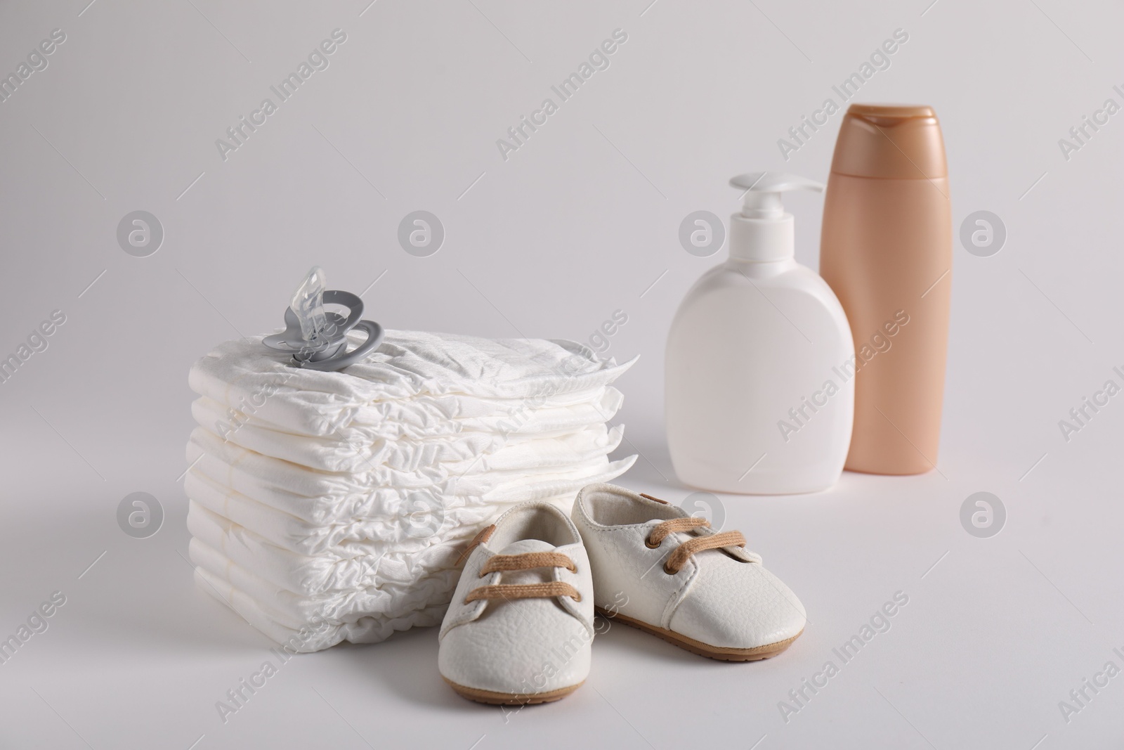 Baby accessories and body care products on light grey background Photo of Baby accessories and body care products on light grey background