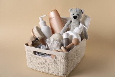 Photo of Baby accessories and body care products in basket on beige background, closeup