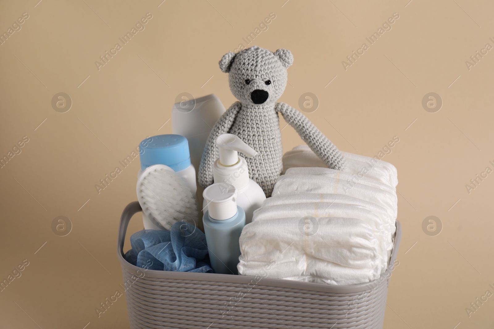 Photo of Baby accessories and body care products in basket on beige background, closeup
