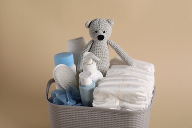 Photo of Baby accessories and body care products in basket on beige background, closeup