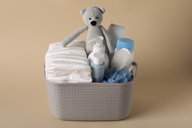 Photo of Baby accessories and body care products in basket on beige background