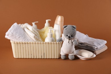 Photo of Baby accessories, clothes and body care products on brown background