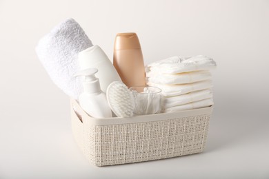 Photo of Baby accessories and body care products in basket on light background