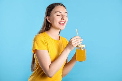 Photo of Woman with refreshing drink and straw on light blue background