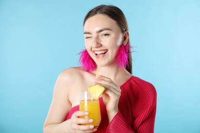 Photo of Woman drinking juice through straw on light blue background