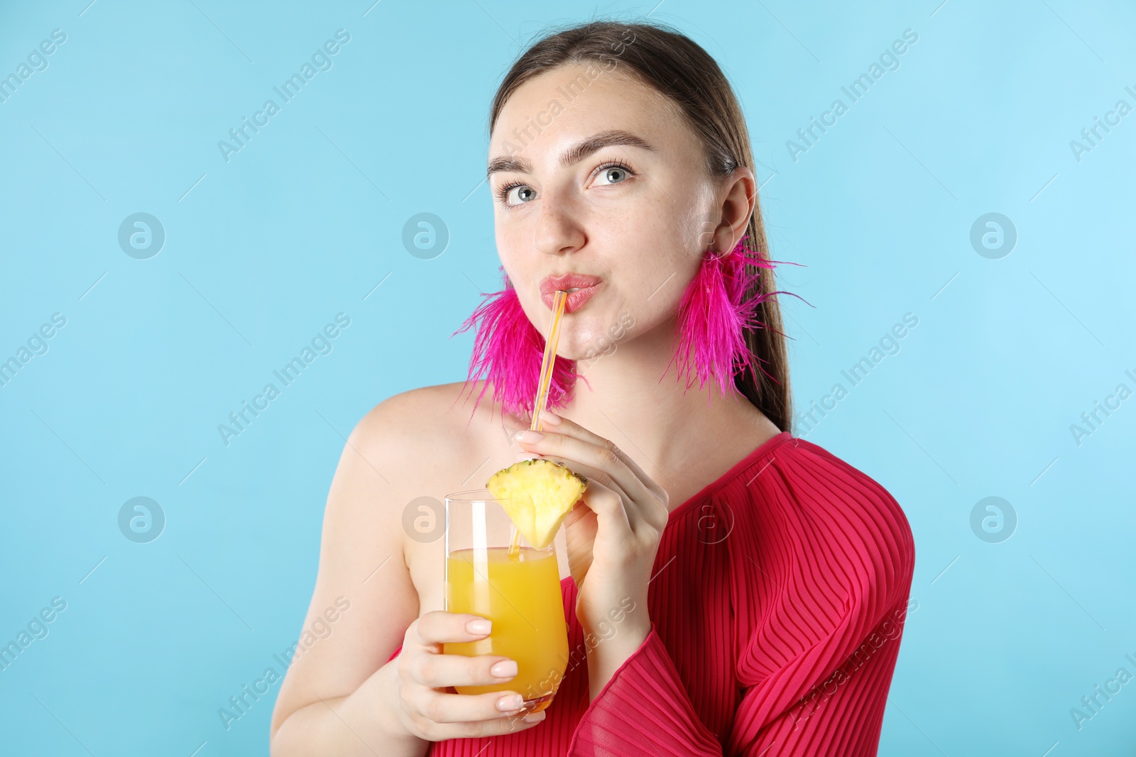 Woman drinking juice through straw on light blue background Photo of Woman drinking juice through straw on light blue background