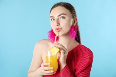 Photo of Woman drinking juice through straw on light blue background