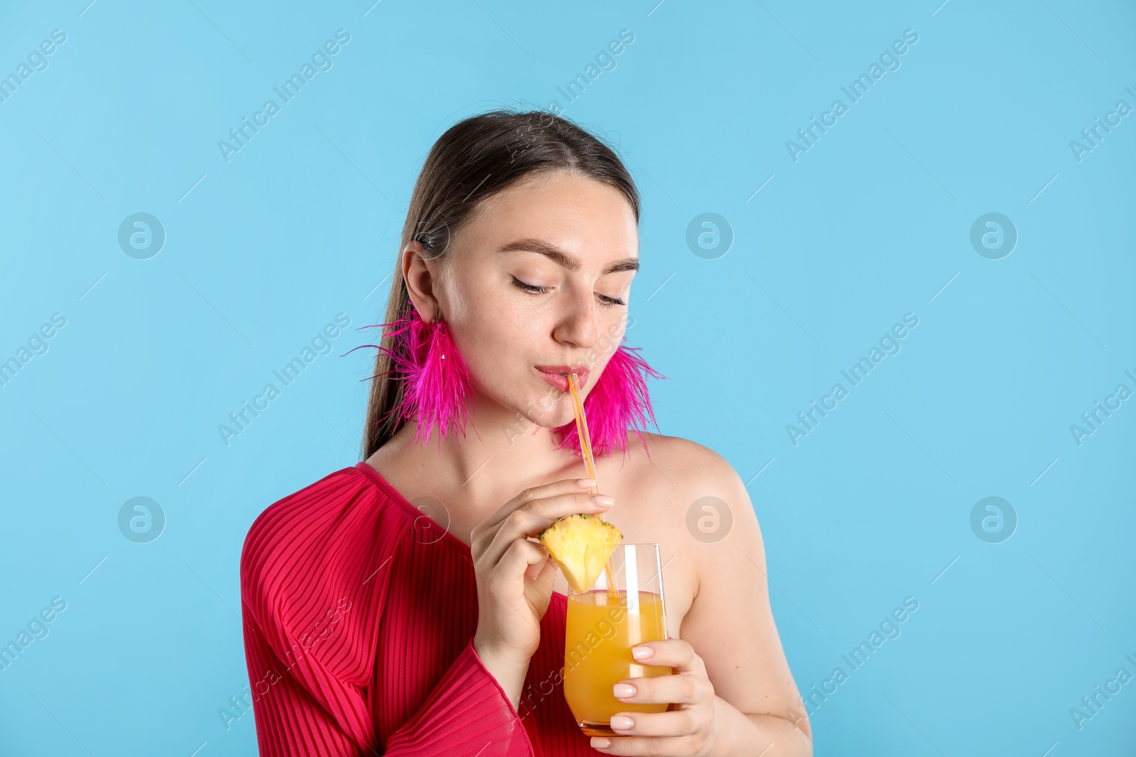 Woman drinking juice through straw on light blue background Photo of Woman drinking juice through straw on light blue background