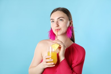 Photo of Woman drinking juice through straw on light blue background
