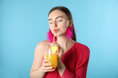 Photo of Woman drinking juice through straw on light blue background