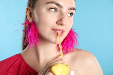 Photo of Woman drinking refreshing drink through straw on light blue background