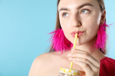 Photo of Woman drinking refreshing drink through straw on light blue background, space for text