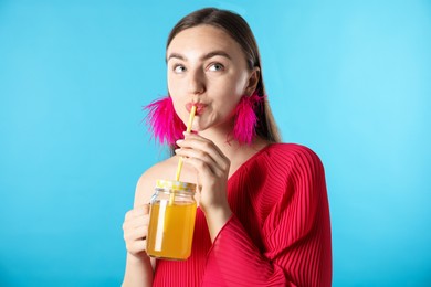 Photo of Woman drinking juice through straw on light blue background