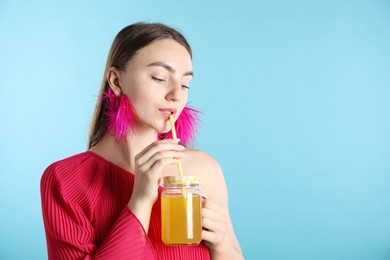 Photo of Woman drinking juice through straw on light blue background, space for text