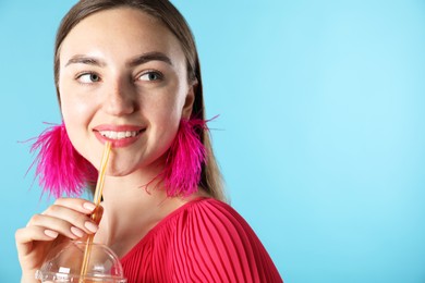 Photo of Woman drinking refreshing drink through straw on light blue background, space for text