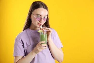 Photo of Woman drinking refreshing drink through straw on orange background, space for text