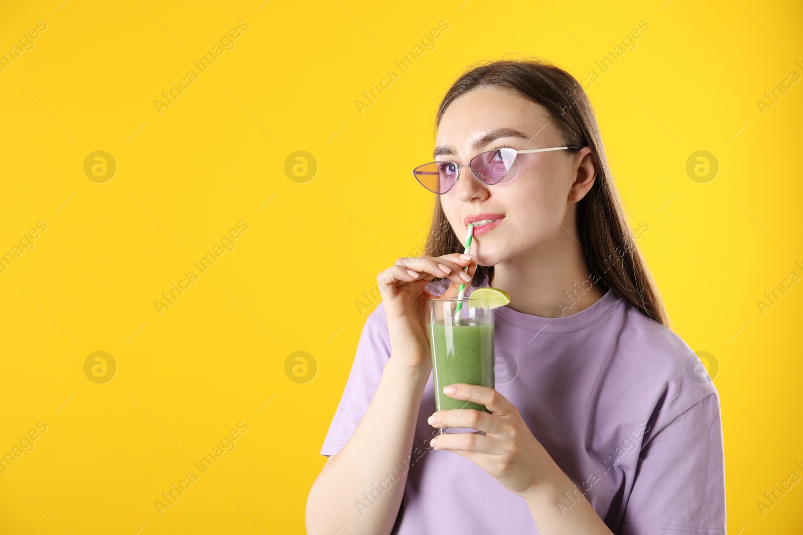 Photo of Woman drinking refreshing drink through straw on orange background, space for text