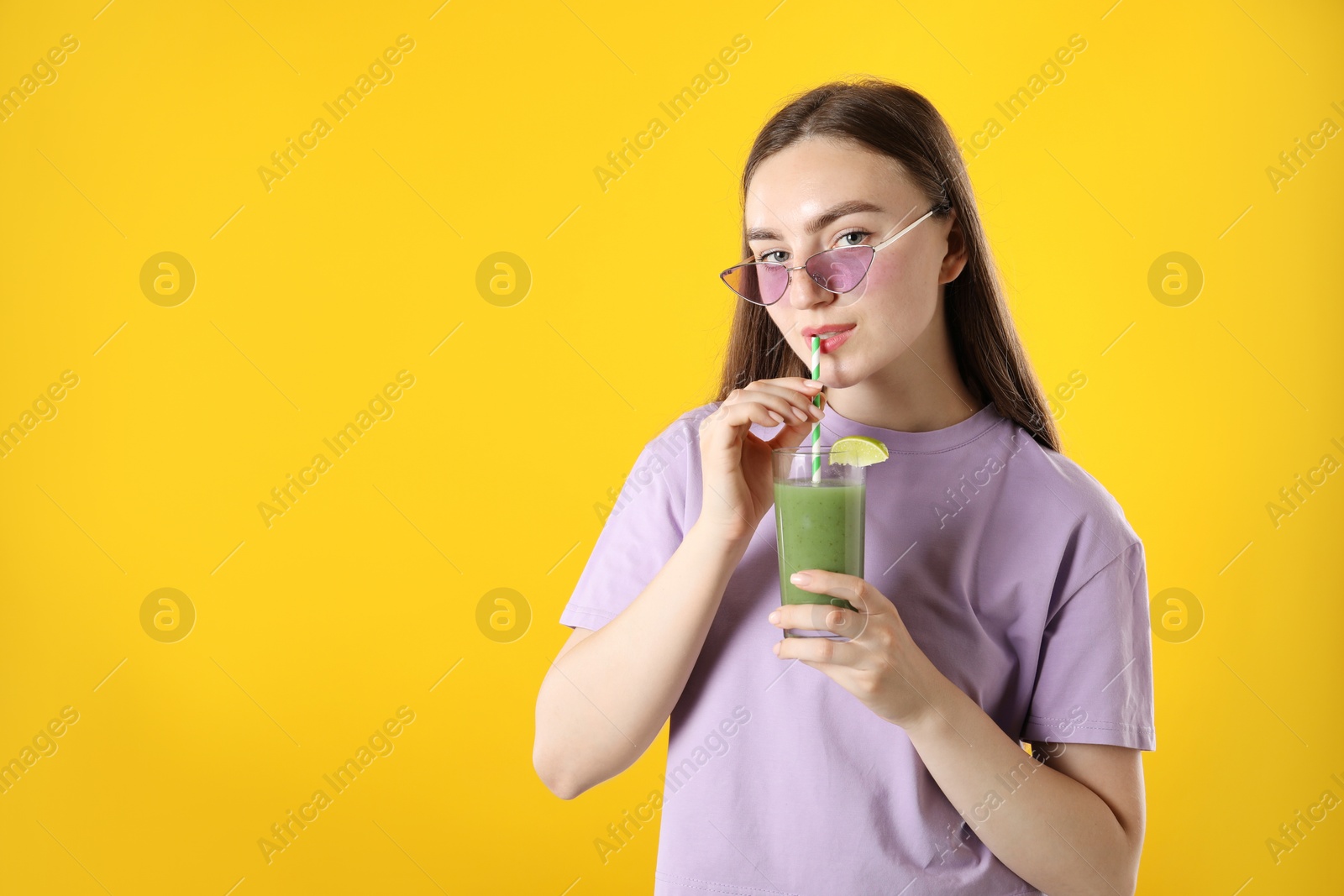 Photo of Woman drinking refreshing drink through straw on orange background, space for text
