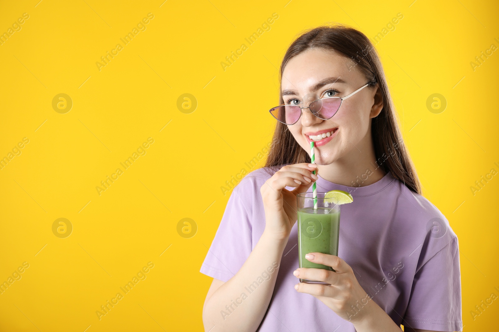 Photo of Woman drinking refreshing drink through straw on orange background, space for text