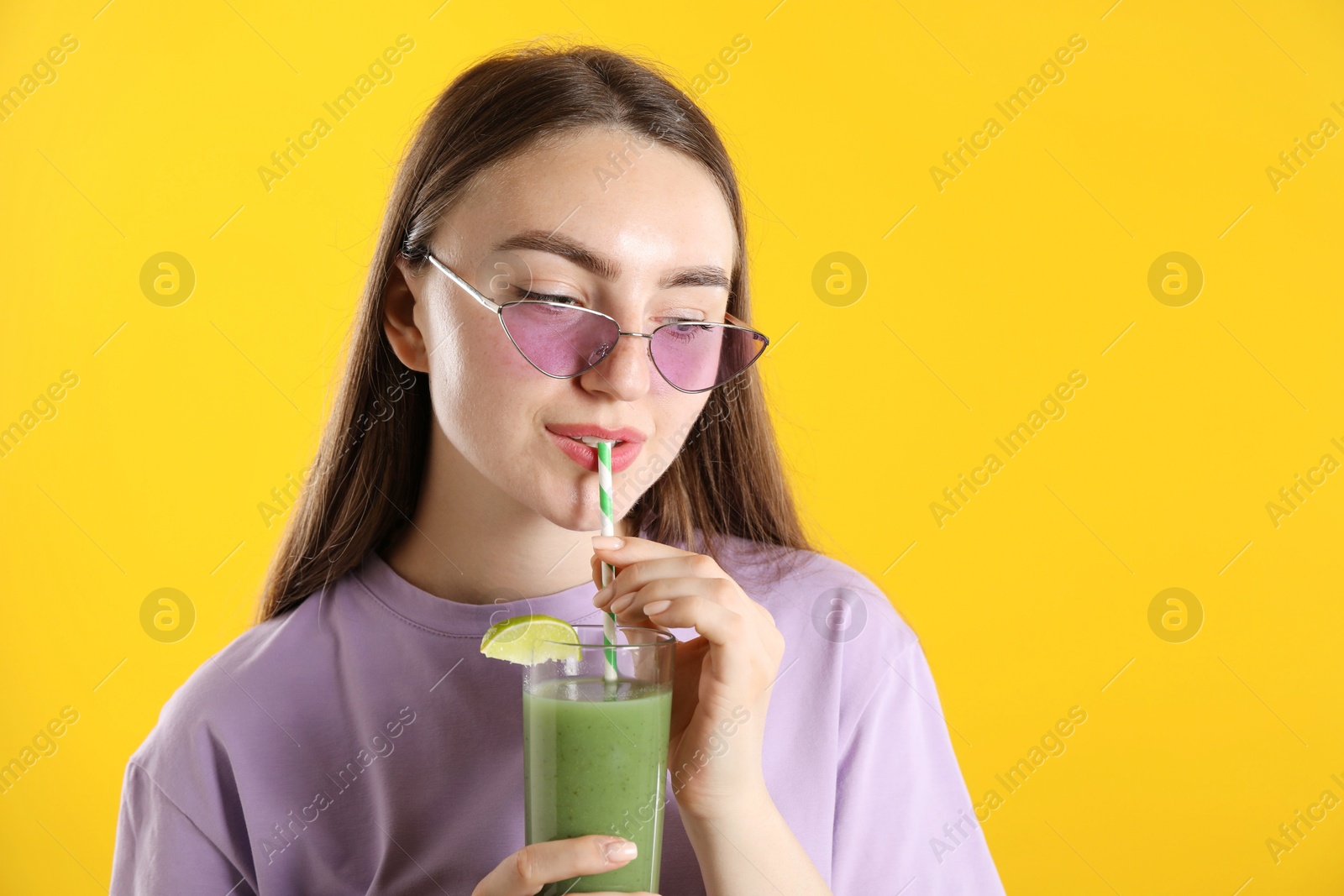 Photo of Woman drinking refreshing drink through straw on orange background, space for text