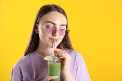 Photo of Woman drinking refreshing drink through straw on orange background, space for text