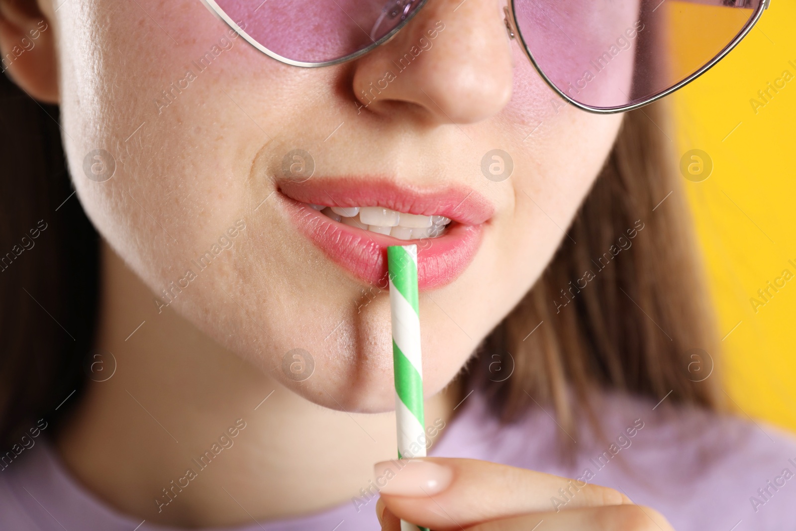 Woman with drinking straw on orange background, closeup Photo of Woman with drinking straw on orange background, closeup