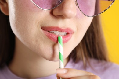 Photo of Woman with drinking straw on orange background, closeup